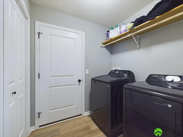 laundry area with washing machine and dryer, light wood-type flooring, and a textured ceiling