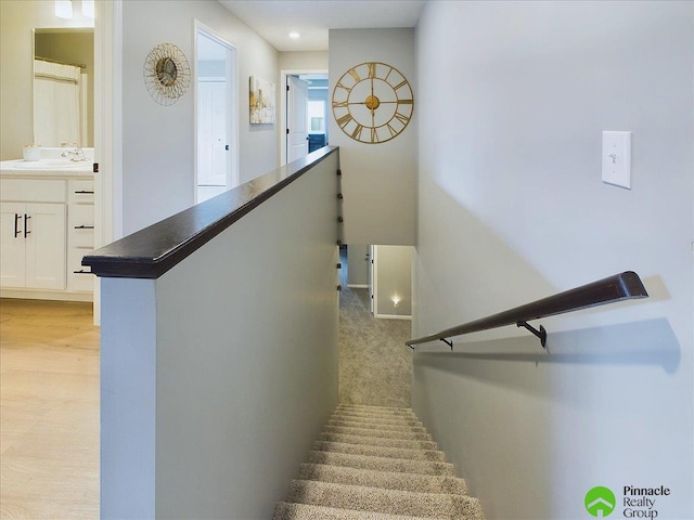 staircase with wood-type flooring and sink