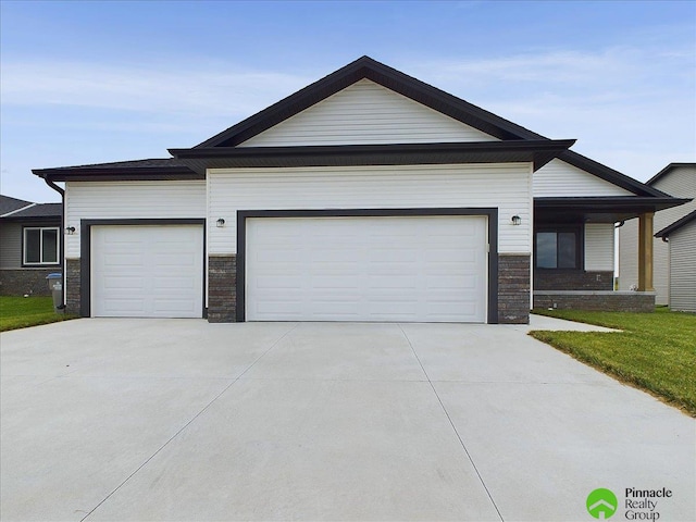 view of front of property with stone siding, an attached garage, and driveway