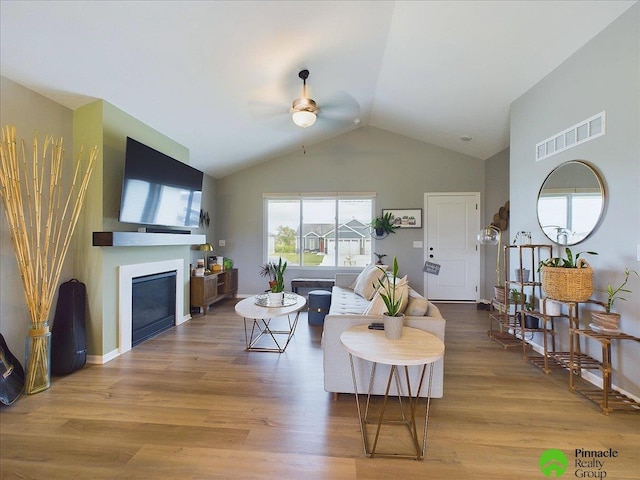 living area with a fireplace, wood finished floors, visible vents, and ceiling fan