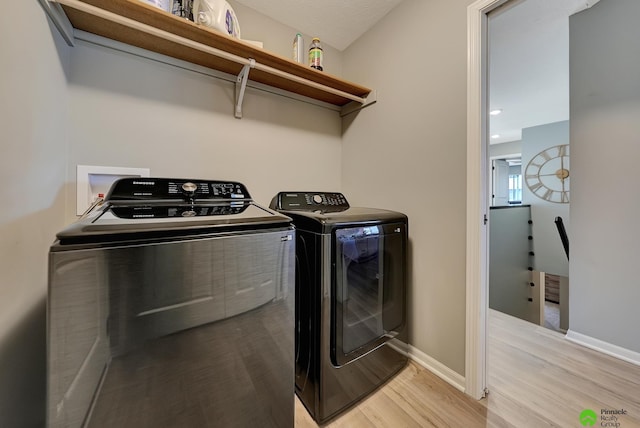 washroom featuring laundry area, light wood-type flooring, baseboards, and separate washer and dryer