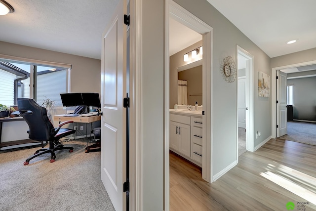 home office featuring plenty of natural light, baseboards, light wood-type flooring, and a sink