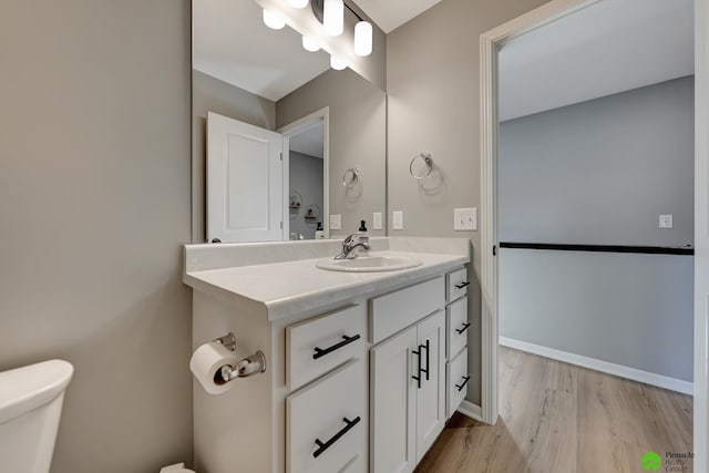 bathroom with baseboards, toilet, wood finished floors, and vanity