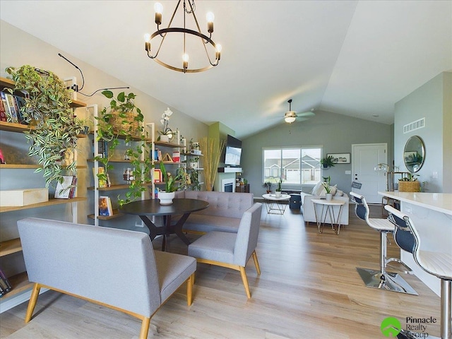 dining area with vaulted ceiling, ceiling fan with notable chandelier, and light wood-type flooring