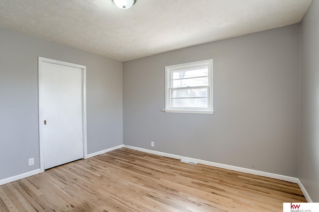 spare room featuring a textured ceiling and light hardwood / wood-style flooring