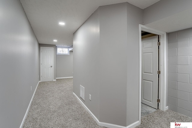 hall featuring light carpet and a textured ceiling