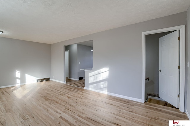 unfurnished room featuring a textured ceiling and light hardwood / wood-style flooring