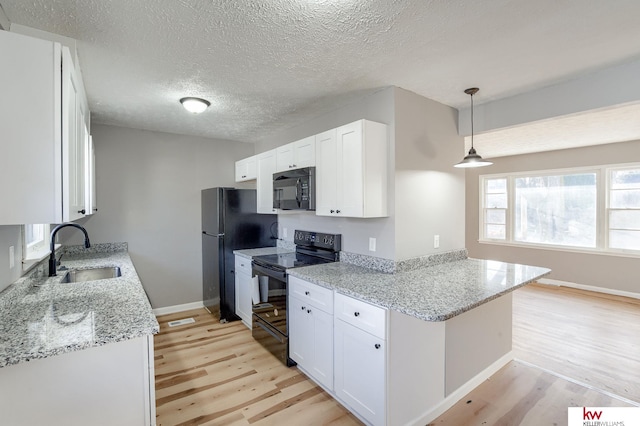 kitchen with black appliances, sink, light hardwood / wood-style flooring, decorative light fixtures, and white cabinetry