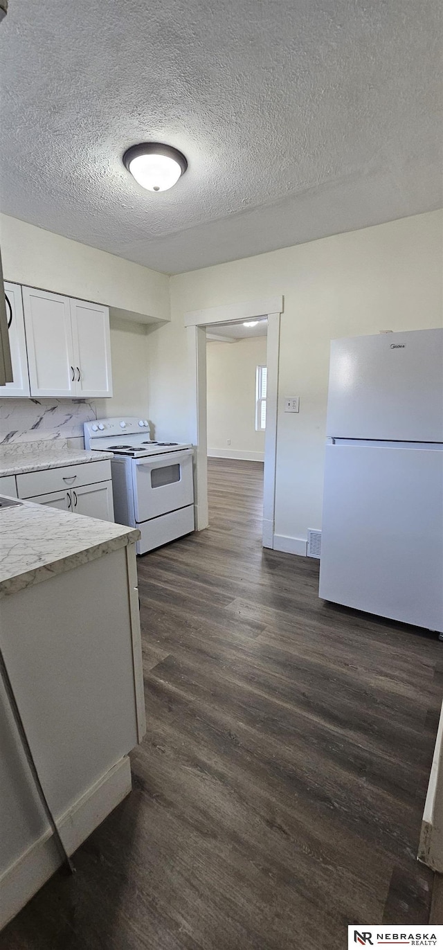 kitchen featuring white appliances, dark hardwood / wood-style floors, light stone countertops, a textured ceiling, and white cabinetry