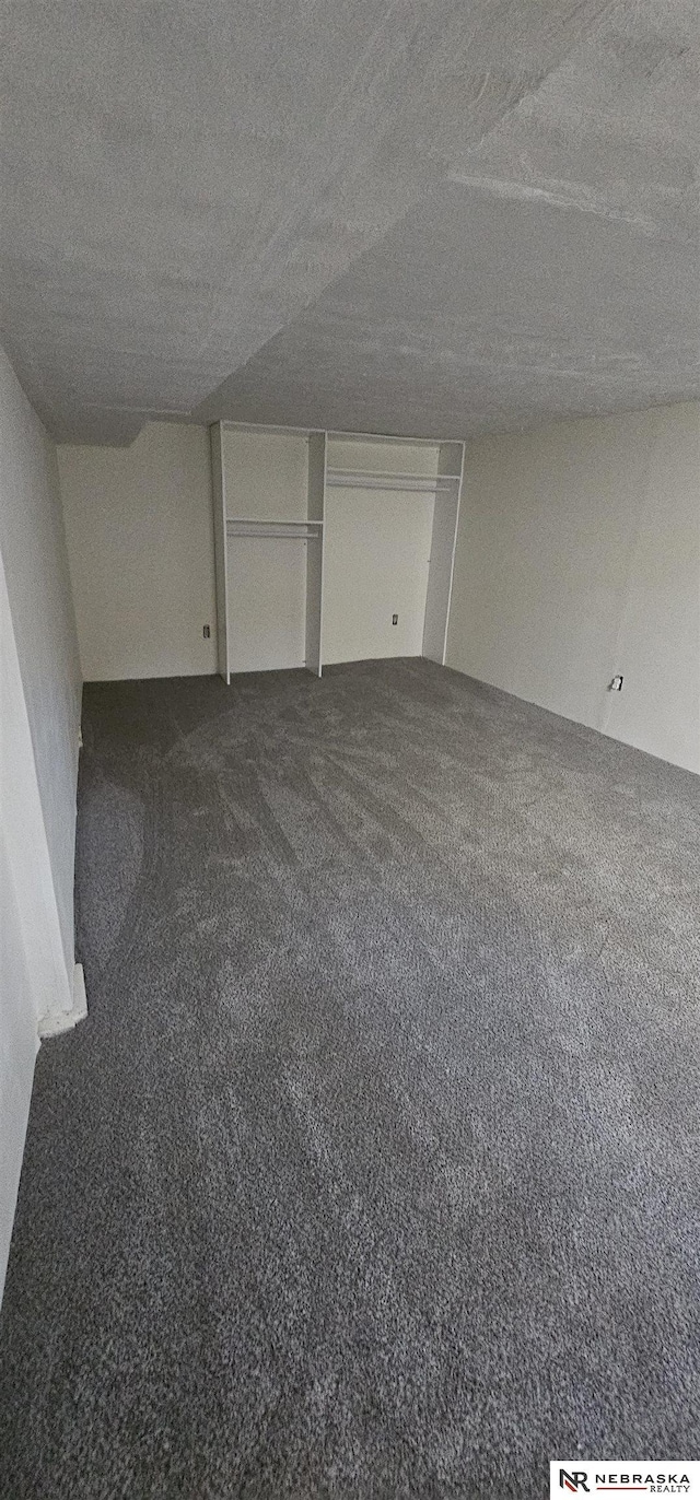 unfurnished bedroom featuring a textured ceiling and dark carpet