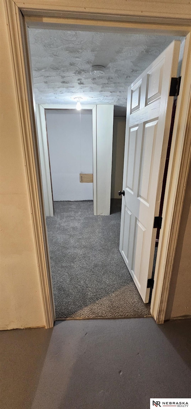 hallway featuring carpet floors and a textured ceiling