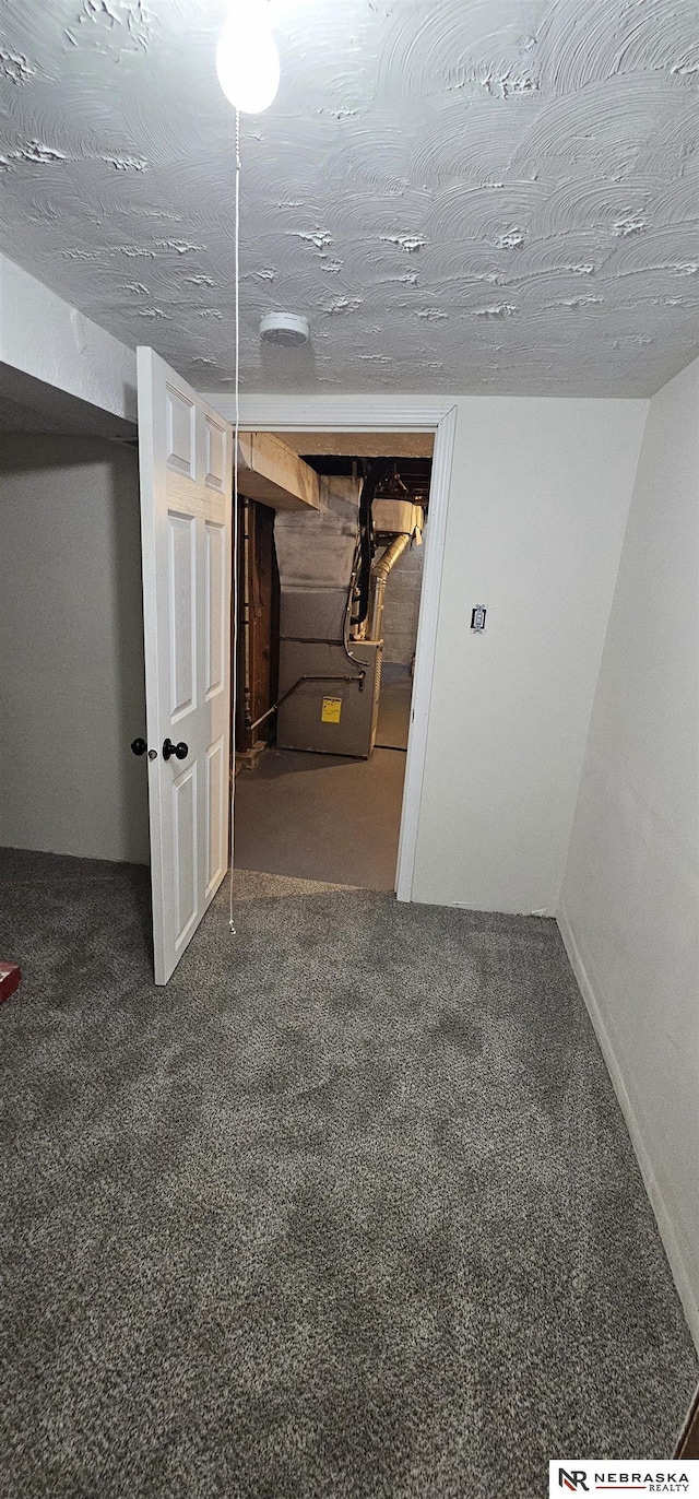 basement featuring dark colored carpet and a textured ceiling