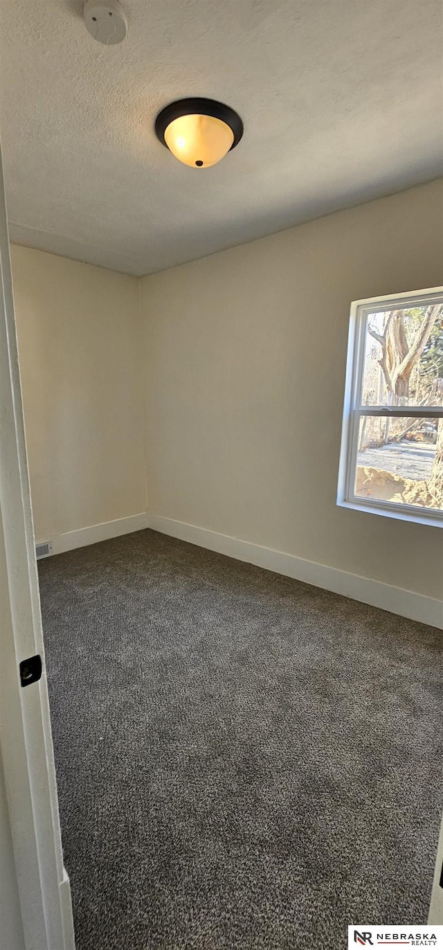 carpeted empty room with a textured ceiling