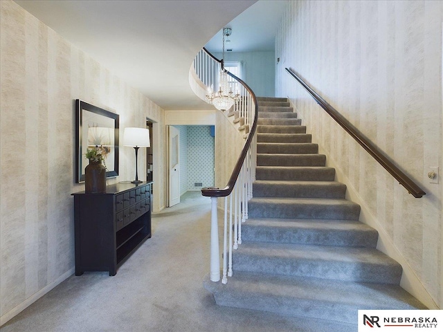 stairway with carpet and an inviting chandelier