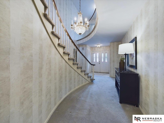 carpeted entryway with a towering ceiling and a chandelier