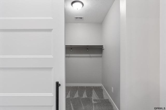 walk in closet with dark carpet