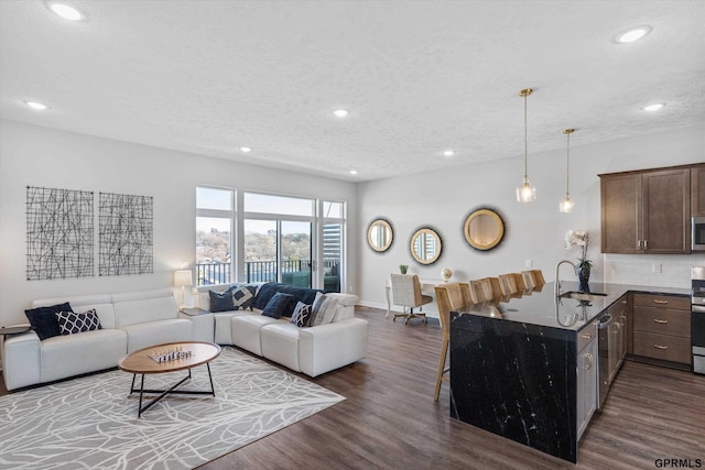 living area featuring recessed lighting, dark wood finished floors, and a textured ceiling