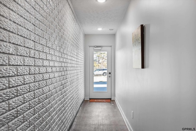 entryway with a textured ceiling, dark hardwood / wood-style floors, and brick wall