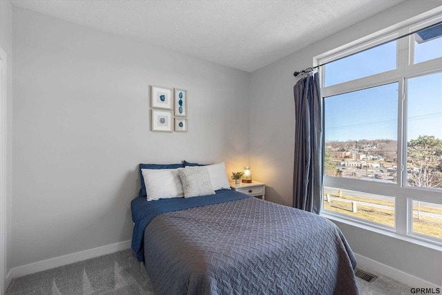 carpeted bedroom with baseboards, visible vents, and a textured ceiling