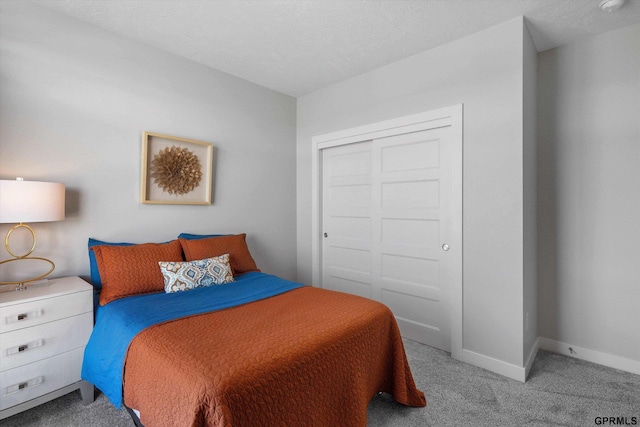 carpeted bedroom with a textured ceiling, a closet, and baseboards