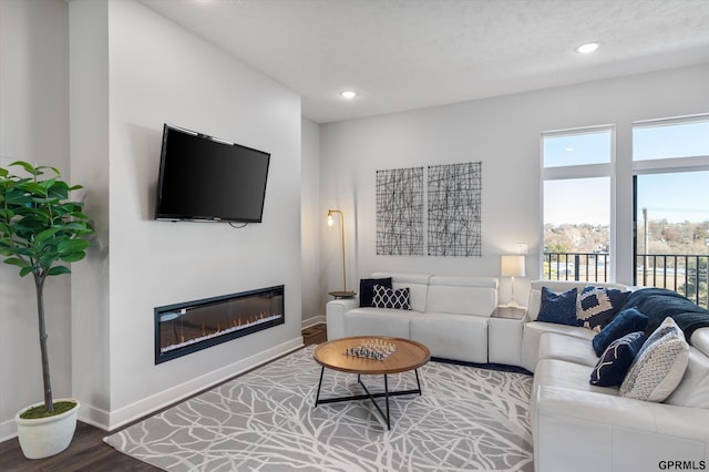 living room featuring recessed lighting, baseboards, wood finished floors, and a glass covered fireplace