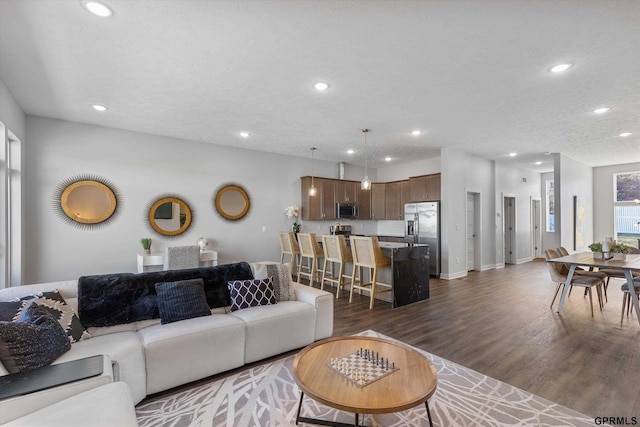 living area featuring dark wood-style floors, baseboards, a textured ceiling, and recessed lighting