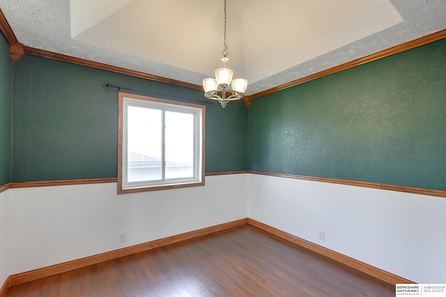 empty room with a chandelier, wood-type flooring, a textured ceiling, and ornamental molding