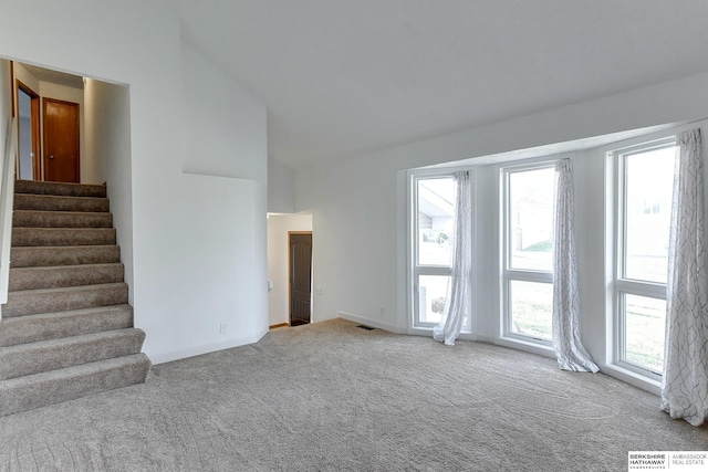 empty room featuring light colored carpet and lofted ceiling