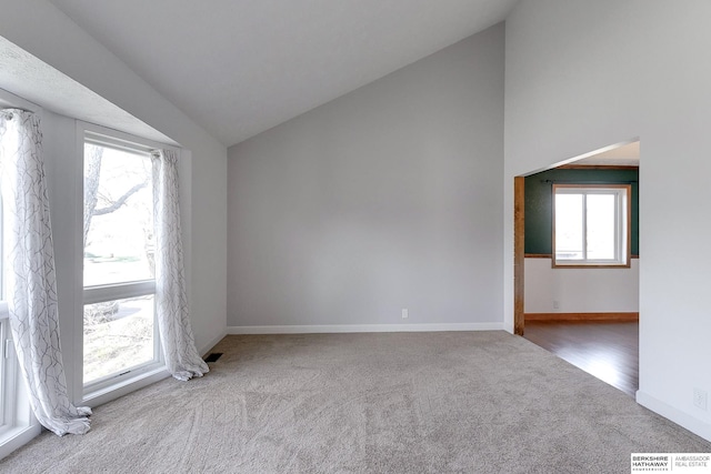 carpeted empty room featuring vaulted ceiling