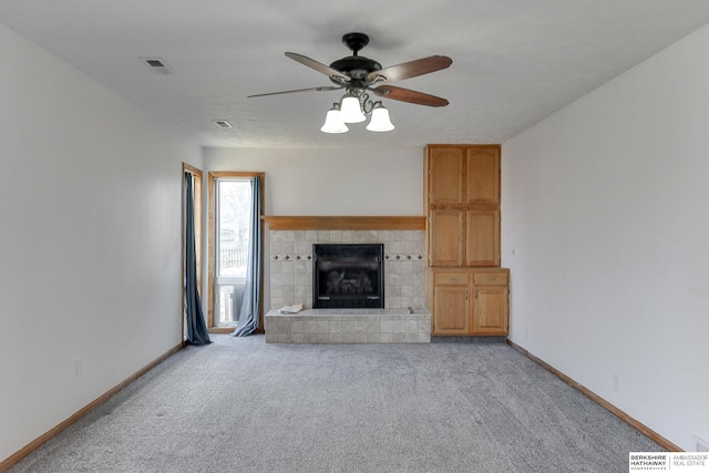 unfurnished living room with ceiling fan, light carpet, and a tiled fireplace