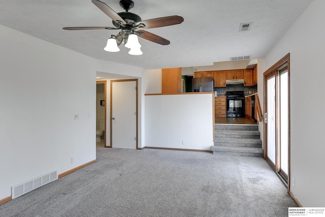 unfurnished living room featuring ceiling fan, a healthy amount of sunlight, and light carpet