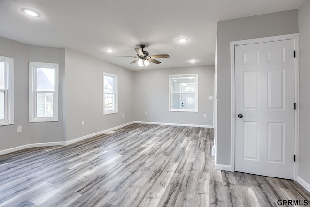 empty room with ceiling fan and light hardwood / wood-style floors