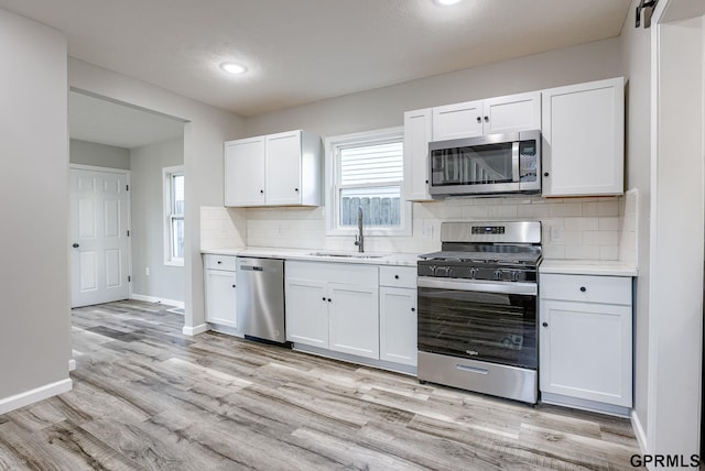 kitchen with white cabinetry, sink, appliances with stainless steel finishes, and light hardwood / wood-style flooring