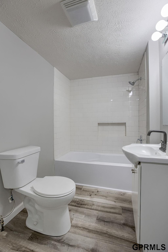 full bathroom featuring vanity, wood-type flooring, a textured ceiling, and toilet