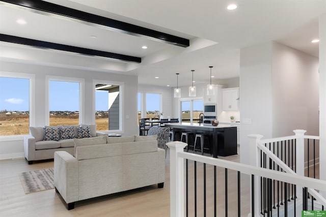 living room with beamed ceiling, light hardwood / wood-style floors, and sink