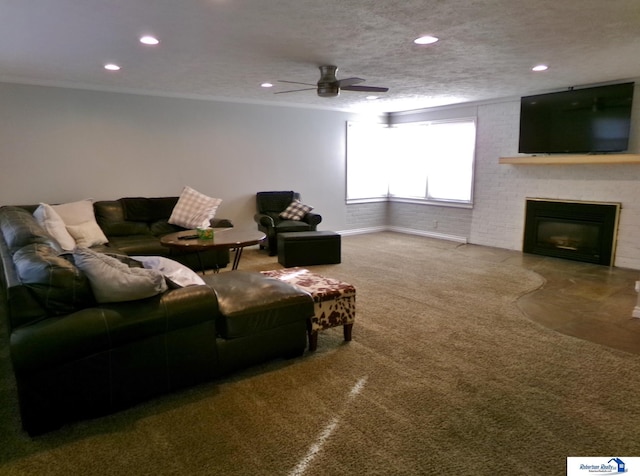 carpeted living room with ceiling fan, a large fireplace, and a textured ceiling