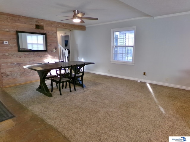 dining room featuring carpet floors, wood walls, ceiling fan, and ornamental molding