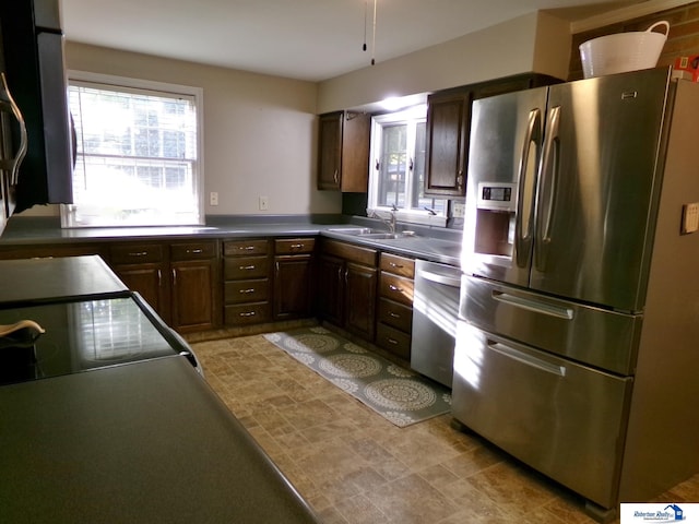 kitchen with appliances with stainless steel finishes, dark brown cabinets, and sink