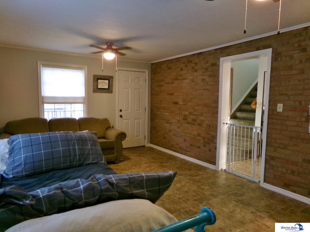 living room featuring ceiling fan, crown molding, and brick wall