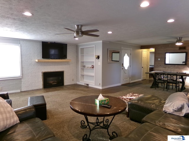 living room with ceiling fan, carpet floors, and a textured ceiling