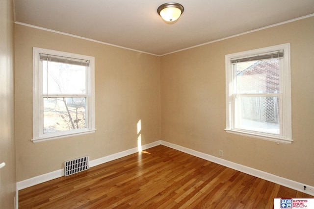 empty room with hardwood / wood-style flooring, a healthy amount of sunlight, and ornamental molding