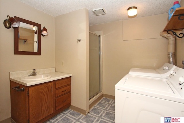 clothes washing area featuring independent washer and dryer, a textured ceiling, and sink