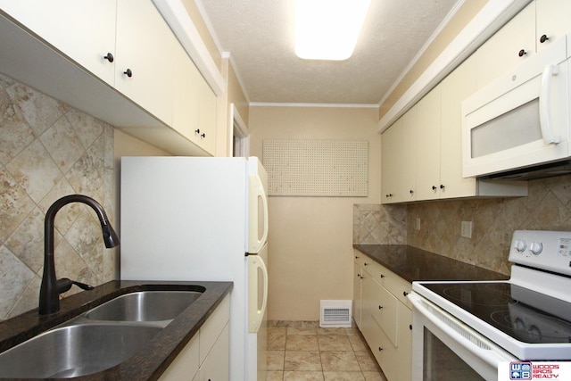 kitchen with white appliances, backsplash, white cabinetry, and sink