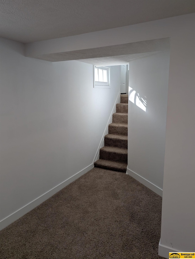 basement with a textured ceiling and dark carpet