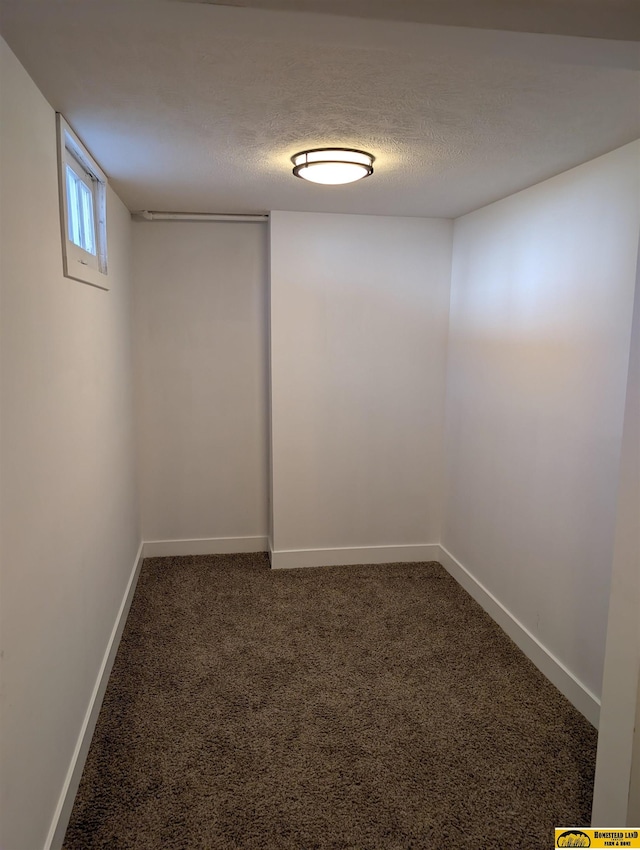 basement featuring a textured ceiling and dark carpet