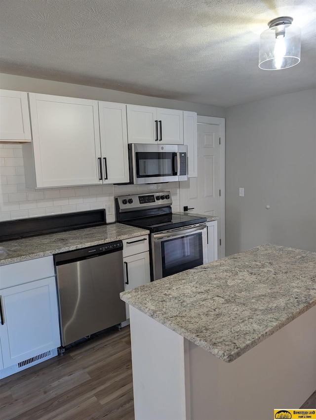 kitchen featuring white cabinets, a textured ceiling, stainless steel appliances, and tasteful backsplash