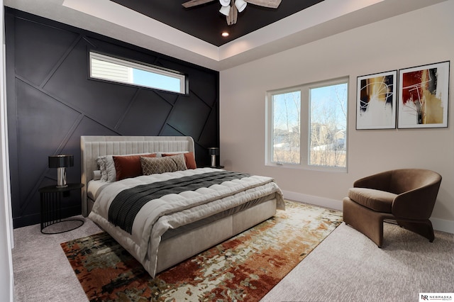 bedroom with a tray ceiling, ceiling fan, and carpet