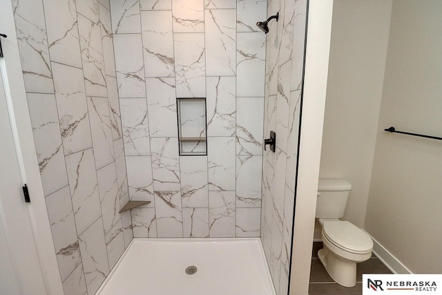 bathroom with tiled shower, tile patterned floors, and toilet