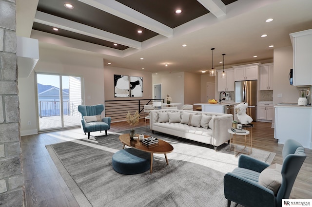 living room with beam ceiling, sink, and light hardwood / wood-style floors