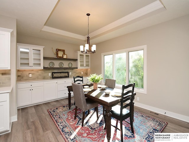 dining area with a raised ceiling, crown molding, dark hardwood / wood-style flooring, and a chandelier